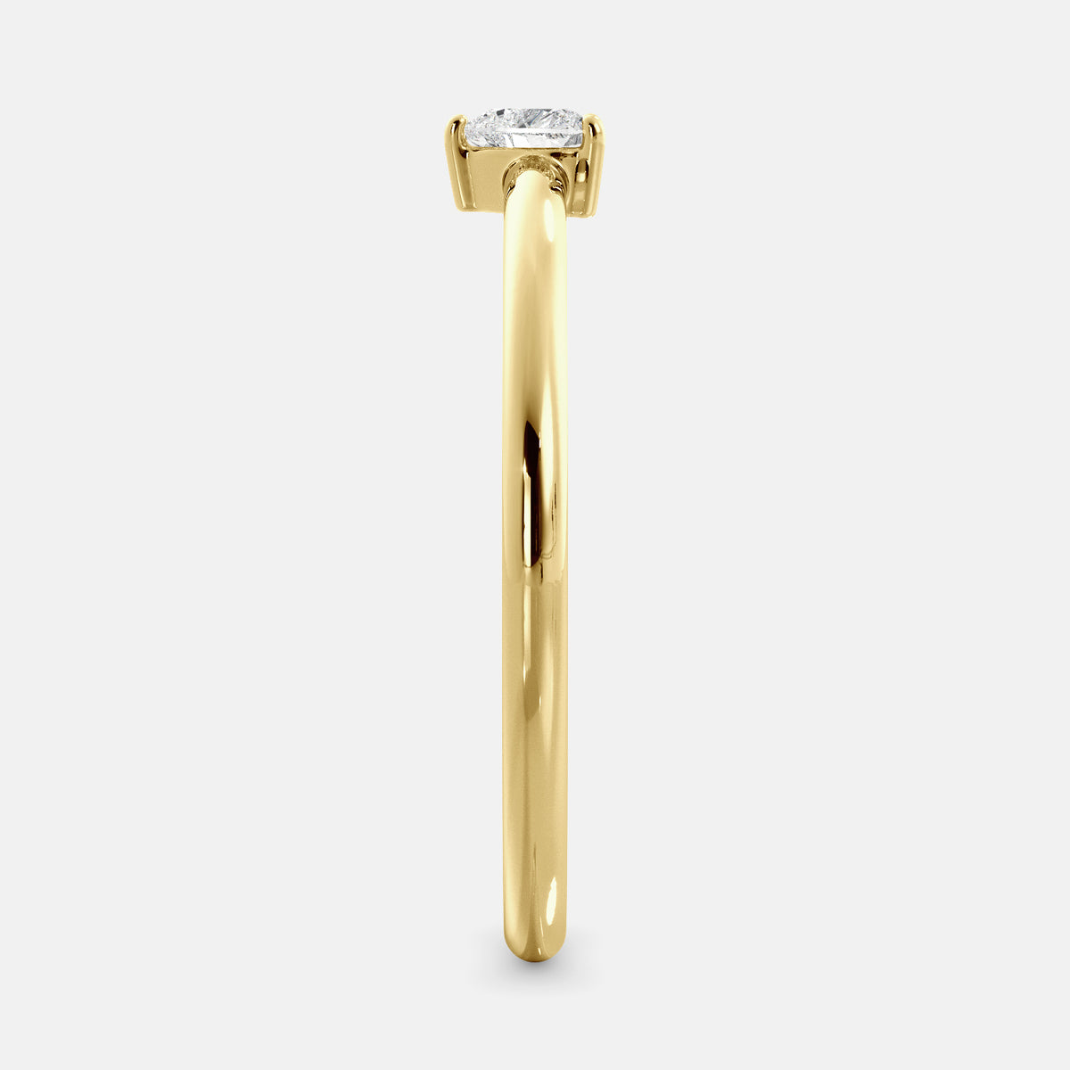 A close-up of a heart-shaped solitaire diamond ring in recycled yellow gold. The ring is set with a single, large diamond in the center of a heart-shaped setting. The ring is made of recycled yellow gold and has a simple, elegant design. The diamond is sparkling and reflects light beautifully. The ring is a perfect gift for a loved one or a special occasion.