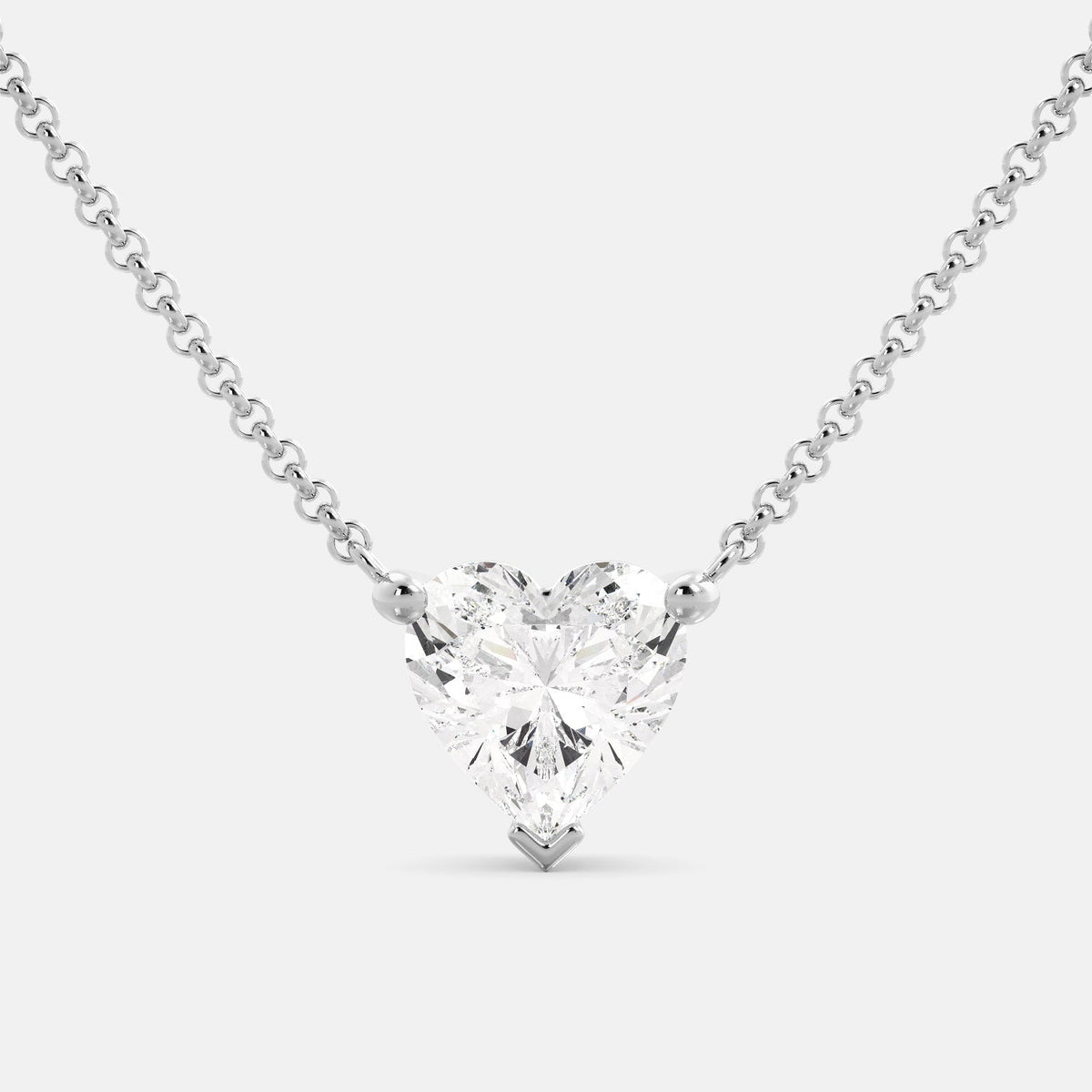 A close-up of a heart-shaped diamond necklace in recycled white gold. The necklace is set with a single heart-shaped diamond in the center of a pendant. The necklace is made of recycled white gold and has a simple, elegant design. The diamond is sparkling and reflects light beautifully. The necklace is a perfect gift for a loved one or a special occasion.