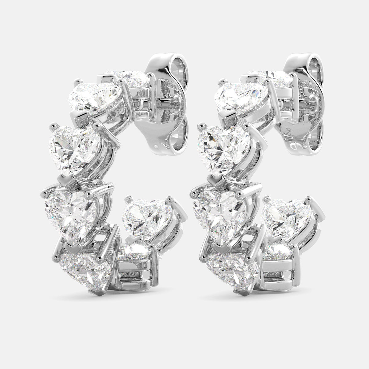 A pair of heart-shaped diamond hoop earrings in recycled white gold. The earrings are made of recycled white gold and have a simple, elegant design. The hoops are approximately 1 inch in diameter and are set with heart-shaped diamonds. The diamonds are sparkling and reflect light beautifully. The earrings are a perfect gift for a loved one or a special occasion.