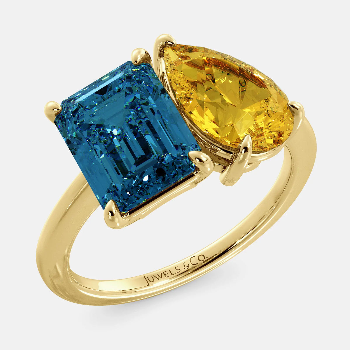 A toi et moi ring with an emerald-cut London Blue Topaz and pear-cut gemstone. The emerald-cut morganite is set on the left of the ring, and the pear-cut gemstone is set on the right. The ring is made of recycled yellow gold and has a simple, elegant design. The pear-cut gemstone can be customized. **Here are some additional details about the image:** * The emerald-cut white London Blue Topaz is a birthstone for December. * The pear-cut gemstone can be customized to any stone of your choice.