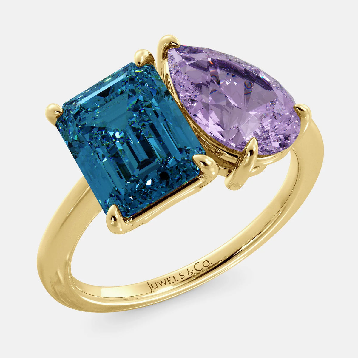 A toi et moi ring with an emerald-cut London Blue Topaz and pear-cut gemstone. The emerald-cut is set on the left of the ring, and the pear-cut gemstone is set on the right. The ring is made of recycled yellow gold and has a simple, elegant design. The pear-cut gemstone can be customized. **Here are some additional details about the image:** * The emerald-cut white London Blue Topaz is a birthstone for December. * The pear-cut gemstone can be customized to any stone of your choice.