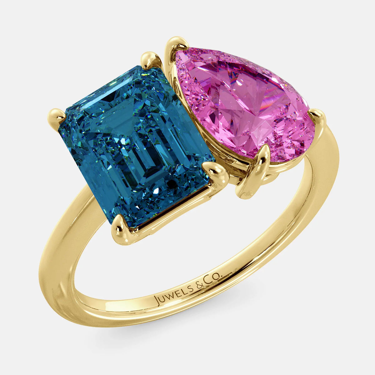 A toi et moi ring with an emerald-cut London Blue Topaz and pear-cut gemstone. The emerald-cut morganite is set on the left of the ring, and the pear-cut gemstone is set on the right. The ring is made of recycled yellow gold and has a simple, elegant design. The pear-cut gemstone can be customized. **Here are some additional details about the image:** * The emerald-cut white London Blue Topaz is a birthstone for December. * The pear-cut gemstone can be customized to any stone of your choice.