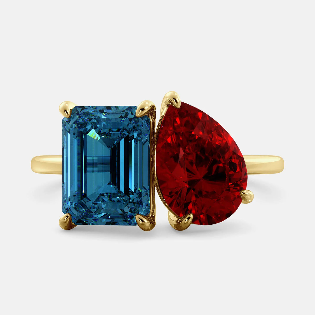 A toi et moi ring with an emerald-cut London Blue Topaz and pear-cut gemstone. The emerald-cut morganite is set on the left of the ring, and the pear-cut gemstone is set on the right. The ring is made of recycled yellow gold and has a simple, elegant design. The pear-cut gemstone can be customized. **Here are some additional details about the image:** * The emerald-cut white London Blue Topaz is a birthstone for December. * The pear-cut gemstone can be customized to any stone of your choice.
