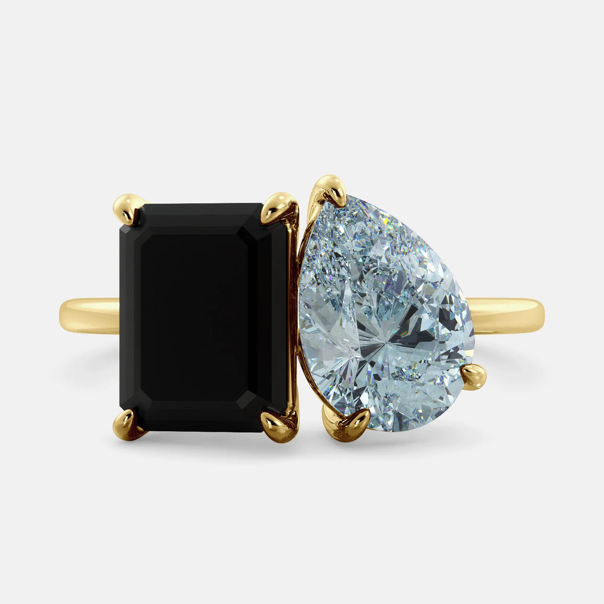 A toi et moi ring with a onyx stone in emerald cut and a pear-shaped stone. The onyx is a deep dark color and the pear-shaped stone can be customized to represent the birth month stone of the wearer or a loved one. The ring is made of 14k gold and is available in all sizes. This ring is a perfect gift for any occasion, and it can be customized to make it truly unique.
