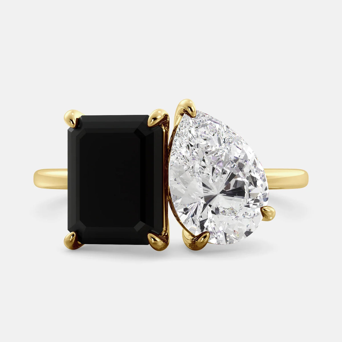 A toi et moi ring with a onyx stone in emerald cut and a pear-shaped stone. The onyx is a deep dark color and the pear-shaped stone can be customized to represent the birth month stone of the wearer or a loved one. The ring is made of 14k gold and is available in all sizes. This ring is a perfect gift for any occasion, and it can be customized to make it truly unique.