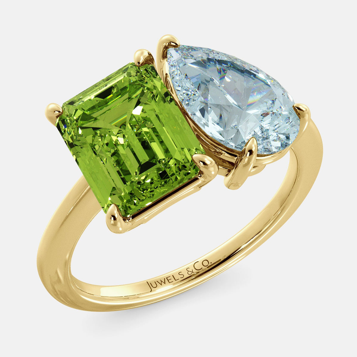 A toi et moi ring with an emerald-cut Green Peridot and a pear-cut gemstone. The emerald-cut morganite is set on the left of the ring, and the pear-cut gemstone is set on the right. The ring is made of recycled yellow gold and has a simple, elegant design. The pear-cut gemstone can be customized. **Here are some additional details about the image:** * The emerald-cut white Green Peridot is a birthstone for August. * The pear-cut gemstone can be customized to any stone of your choice.