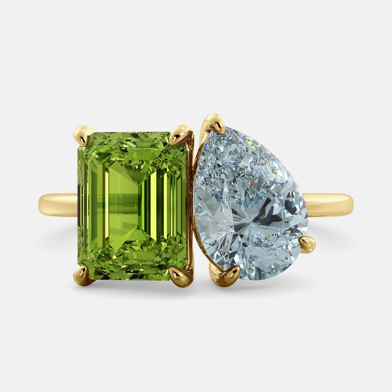 A toi et moi ring with an emerald-cut Green Peridot and a pear-cut gemstone. The emerald-cut morganite is set on the left of the ring, and the pear-cut gemstone is set on the right. The ring is made of recycled yellow gold and has a simple, elegant design. The pear-cut gemstone can be customized. **Here are some additional details about the image:** * The emerald-cut white Green Peridot is a birthstone for August. * The pear-cut gemstone can be customized to any stone of your choice.