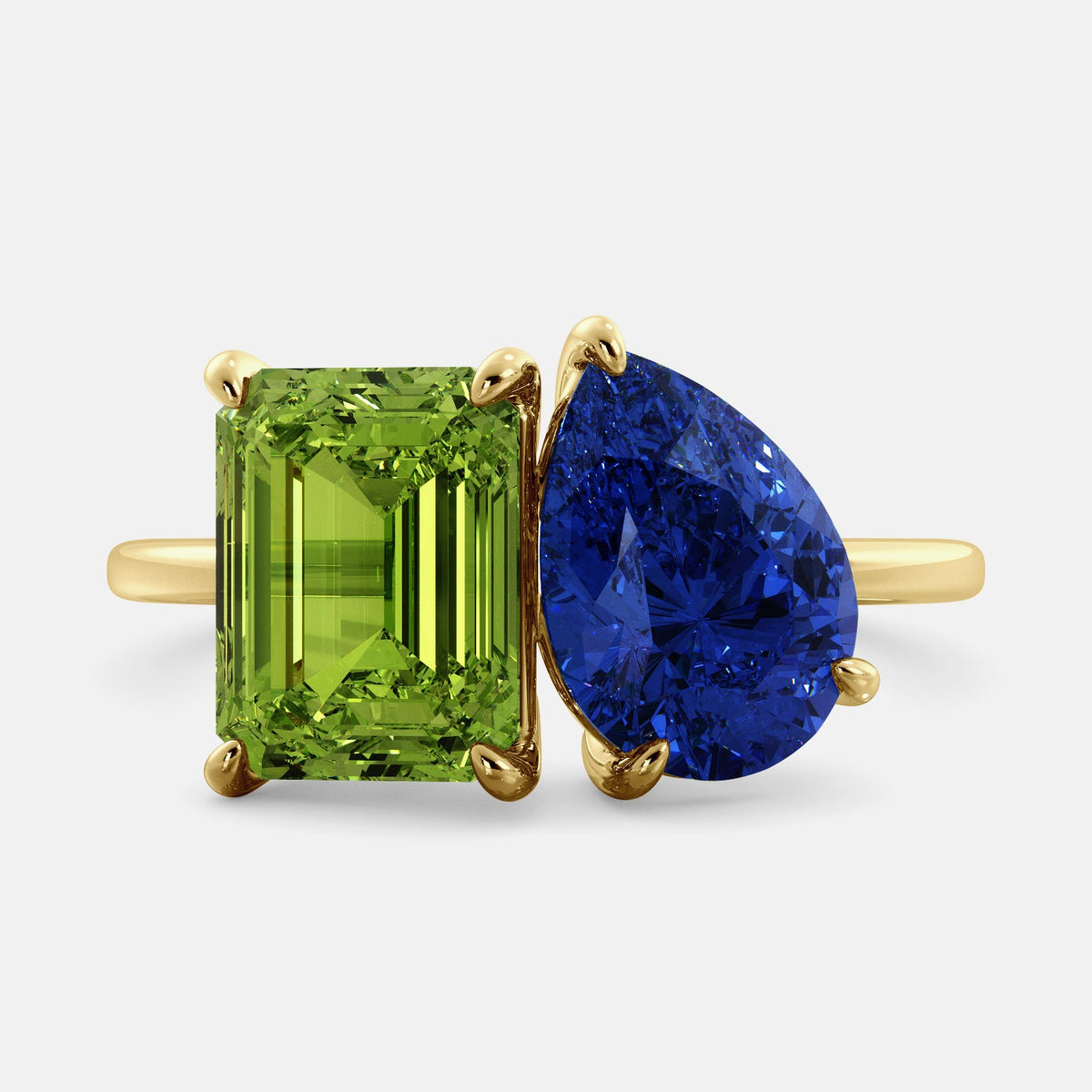 A toi et moi ring with an emerald-cut Green Peridot and a pear-cut gemstone. The emerald-cut morganite is set on the left of the ring, and the pear-cut gemstone is set on the right. The ring is made of recycled yellow gold and has a simple, elegant design. The pear-cut gemstone can be customized. **Here are some additional details about the image:** * The emerald-cut white Green Peridot is a birthstone for August. * The pear-cut gemstone can be customized to any stone of your choice.