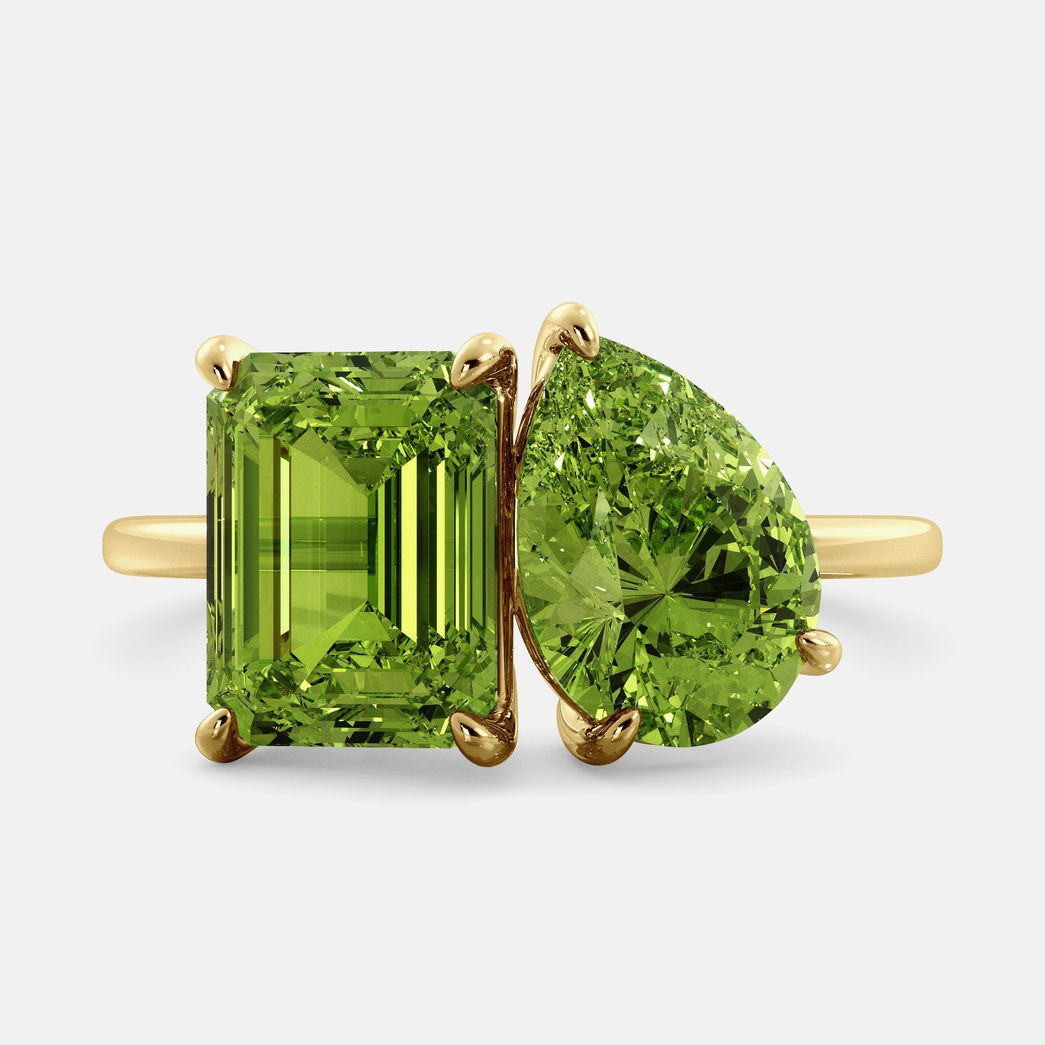 A toi et moi ring with an emerald-cut Green Peridot and a pear-cut gemstone. The emerald-cut morganite is set on the left of the ring, and the pear-cut gemstone is set on the right. The ring is made of recycled yellow gold and has a simple, elegant design. The pear-cut gemstone can be customized. **Here are some additional details about the image:** * The emerald-cut white Green Peridot is a birthstone for August. * The pear-cut gemstone can be customized to any stone of your choice.