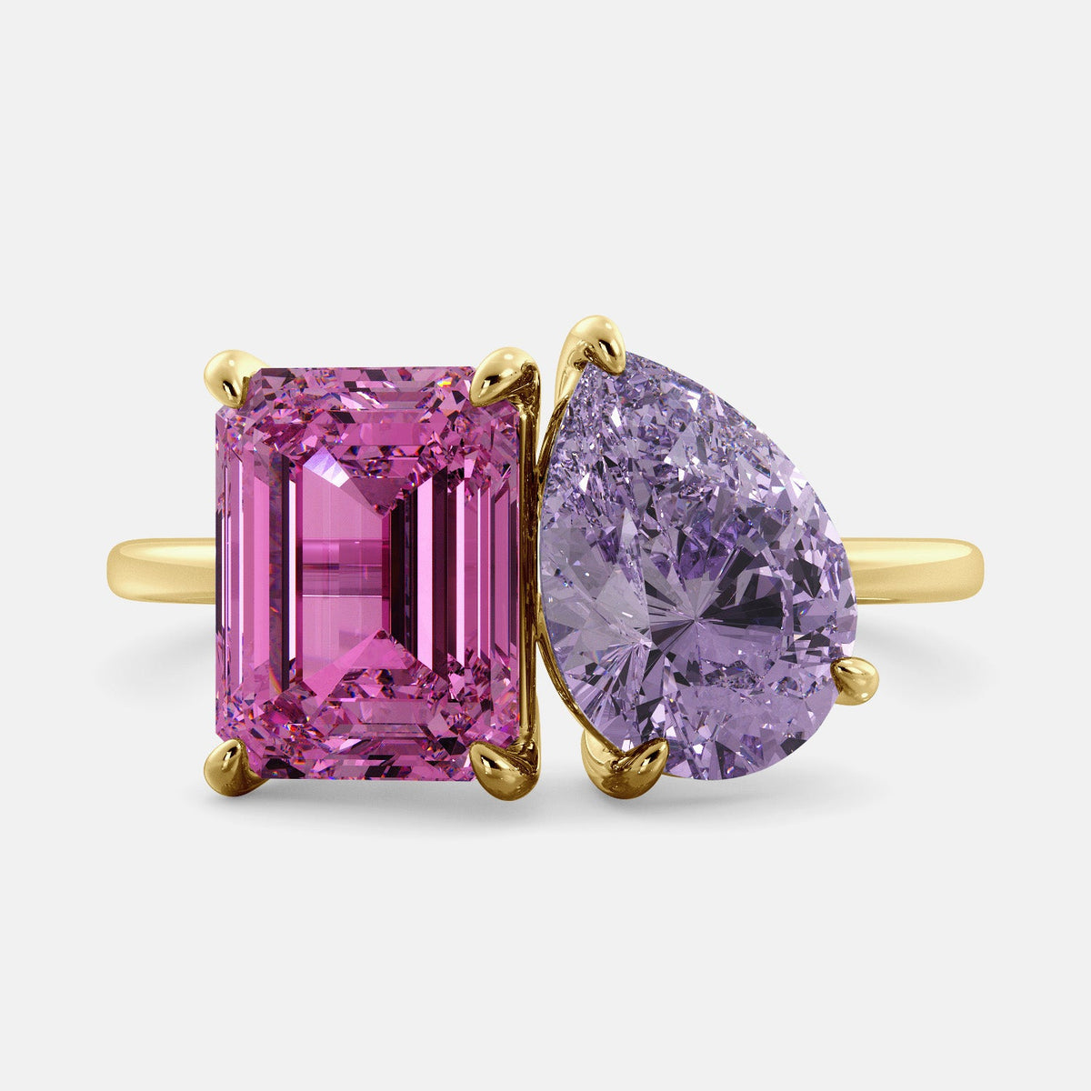 A toi et moi ring with an emerald-cut Pink Sapphire and pear-cut gemstone. The emerald-cut is set on the left of the ring, and the pear-cut gemstone is set on the right. The ring is made of recycled yellow gold and has a simple, elegant design. The pear-cut gemstone can be customized. **Here are some additional details about the image:** * The emerald-cut white Pink Sapphire is a birthstone for October. * The pear-cut gemstone can be customized to any stone of your choice.