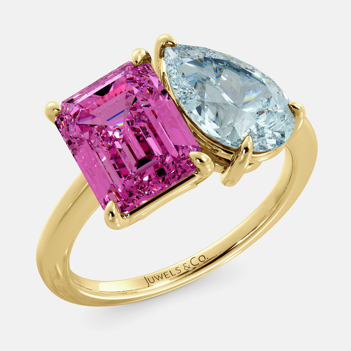 A toi et moi ring with an emerald-cut Pink Sapphire and pear-cut gemstone. The emerald-cut is set on the left of the ring, and the pear-cut gemstone is set on the right. The ring is made of recycled yellow gold and has a simple, elegant design. The pear-cut gemstone can be customized. **Here are some additional details about the image:** * The emerald-cut white Pink Sapphire is a birthstone for October. * The pear-cut gemstone can be customized to any stone of your choice.