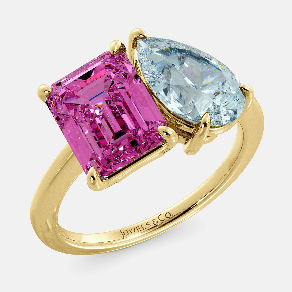 A toi et moi ring with an emerald-cut Pink Sapphire and pear-cut gemstone. The emerald-cut morganite is set on the left of the ring, and the pear-cut gemstone is set on the right. The ring is made of recycled yellow gold and has a simple, elegant design. The pear-cut gemstone can be customized. **Here are some additional details about the image:** * The emerald-cut white Pink Sapphire is a birthstone for October. * The pear-cut gemstone can be customized to any stone of your choice.