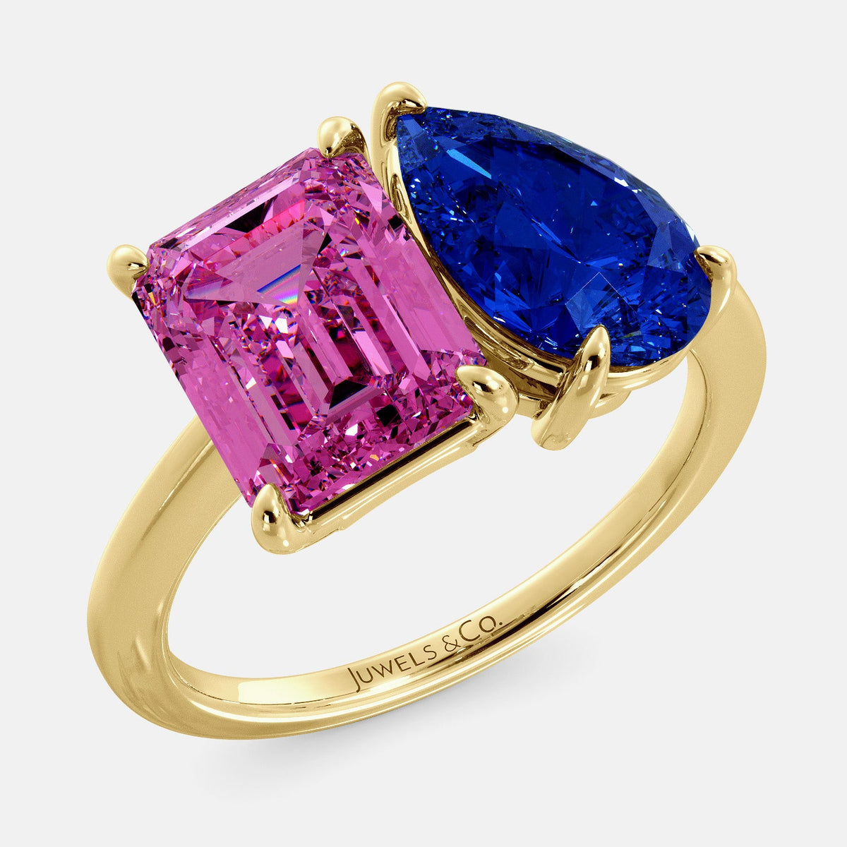 A toi et moi ring with an emerald-cut Pink Sapphire and pear-cut gemstone. The emerald-cut is set on the left of the ring, and the pear-cut gemstone is set on the right. The ring is made of recycled yellow gold and has a simple, elegant design. The pear-cut gemstone can be customized. **Here are some additional details about the image:** * The emerald-cut white Pink Sapphire is a birthstone for October. * The pear-cut gemstone can be customized to any stone of your choice.