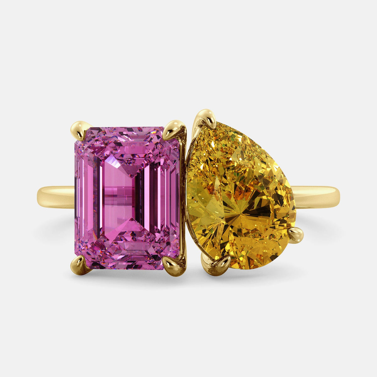 A toi et moi ring with an emerald-cut Pink Sapphire and pear-cut gemstone. The emerald-cut is set on the left of the ring, and the pear-cut gemstone is set on the right. The ring is made of recycled yellow gold and has a simple, elegant design. The pear-cut gemstone can be customized. **Here are some additional details about the image:** * The emerald-cut white Pink Sapphire is a birthstone for October. * The pear-cut gemstone can be customized to any stone of your choice.