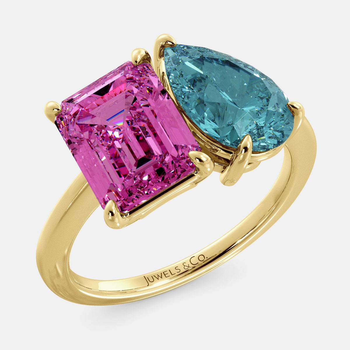 A toi et moi ring with an emerald-cut Pink Sapphire and pear-cut gemstone. The emerald-cut is set on the left of the ring, and the pear-cut gemstone is set on the right. The ring is made of recycled yellow gold and has a simple, elegant design. The pear-cut gemstone can be customized. **Here are some additional details about the image:** * The emerald-cut white Pink Sapphire is a birthstone for October. * The pear-cut gemstone can be customized to any stone of your choice.
