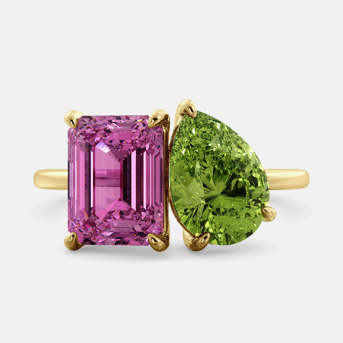 A toi et moi ring with an emerald-cut Pink Sapphire and pear-cut gemstone. The emerald-cut is set on the left of the ring, and the pear-cut gemstone is set on the right. The ring is made of recycled yellow gold and has a simple, elegant design. The pear-cut gemstone can be customized. **Here are some additional details about the image:** * The emerald-cut white Pink Sapphire is a birthstone for October. * The pear-cut gemstone can be customized to any stone of your choice.