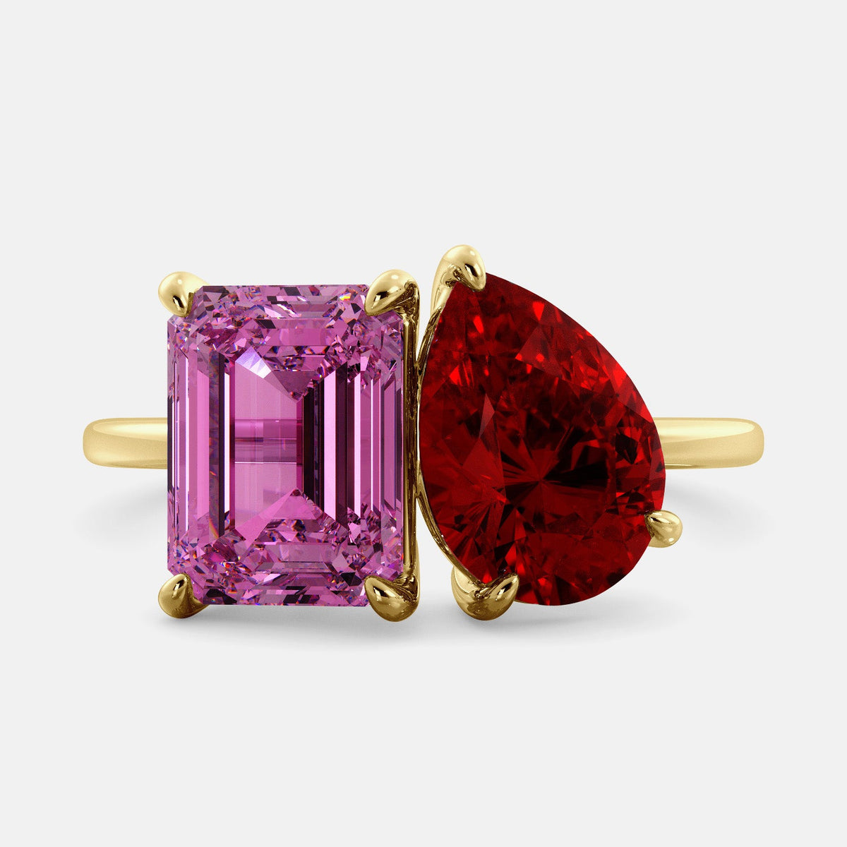 A toi et moi ring with an emerald-cut Pink Sapphire and pear-cut gemstone. The emerald-cut is set on the left of the ring, and the pear-cut gemstone is set on the right. The ring is made of recycled yellow gold and has a simple, elegant design. The pear-cut gemstone can be customized. **Here are some additional details about the image:** * The emerald-cut white Pink Sapphire is a birthstone for October. * The pear-cut gemstone can be customized to any stone of your choice.