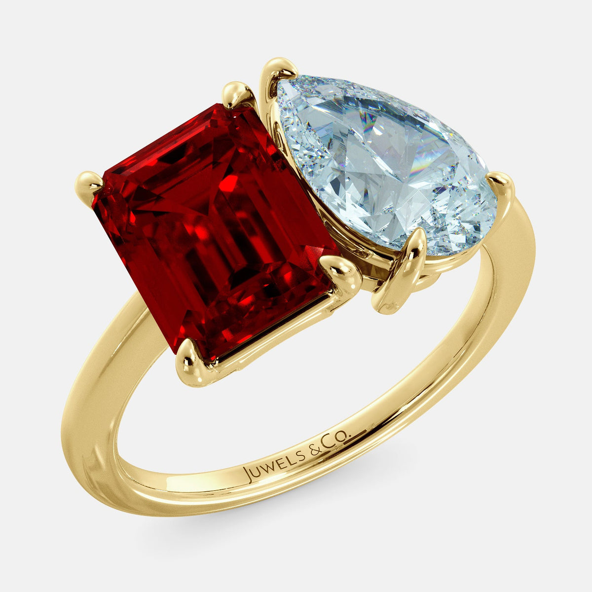 A toi et moi ring with an emerald-cut ruby and a pear-cut gemstone. The emerald-cut morganite is set on the left of the ring, and the pear-cut gemstone is set on the right. The ring is made of recycled yellow gold and has a simple, elegant design. The pear-cut gemstone can be customized. **Here are some additional details about the image:** * The emerald-cut white ruby is a birthstone for July. * The pear-cut gemstone can be customized to any stone of your choice.