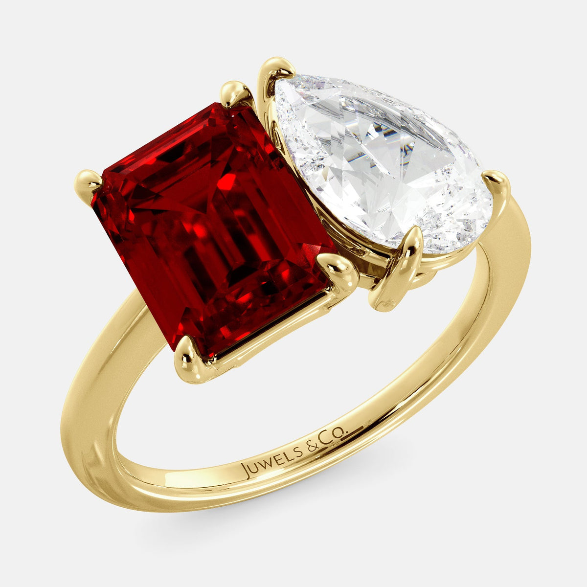 A toi et moi ring with an emerald-cut ruby and a pear-cut gemstone. The emerald-cut is set on the left of the ring, and the pear-cut gemstone is set on the right. The ring is made of recycled yellow gold and has a simple, elegant design. The pear-cut gemstone can be customized. **Here are some additional details about the image:** * The emerald-cut white ruby is a birthstone for July. * The pear-cut gemstone can be customized to any stone of your choice.