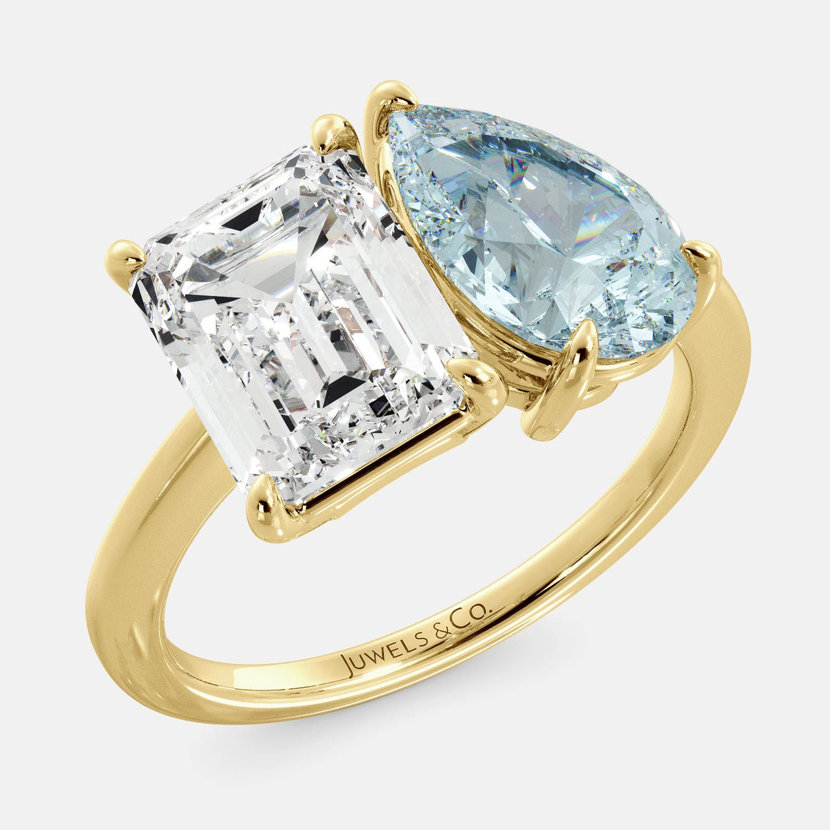 A toi et moi ring with an emerald-cut white topaz and a pear-cut gemstone. The emerald-cut morganite is set on the left of the ring, and the pear-cut gemstone is set on the right. The ring is made of recycled yellow gold and has a simple, elegant design. The pear-cut gemstone can be customized. **Here are some additional details about the image:** * The emerald-cut white topaz is a birthstone for April. * The pear-cut gemstone can be customized to any stone of your choice.