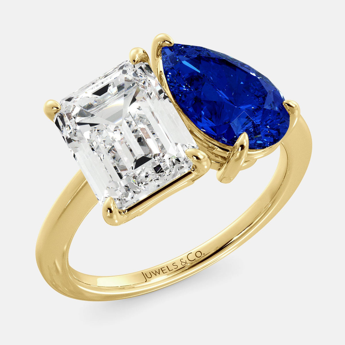 A toi et moi ring with an emerald-cut white topaz and a pear-cut gemstone. The emerald-cut morganite is set on the left of the ring, and the pear-cut gemstone is set on the right. The ring is made of recycled yellow gold and has a simple, elegant design. The pear-cut gemstone can be customized. **Here are some additional details about the image:** * The emerald-cut white topaz is a birthstone for April. * The pear-cut gemstone can be customized to any stone of your choice.