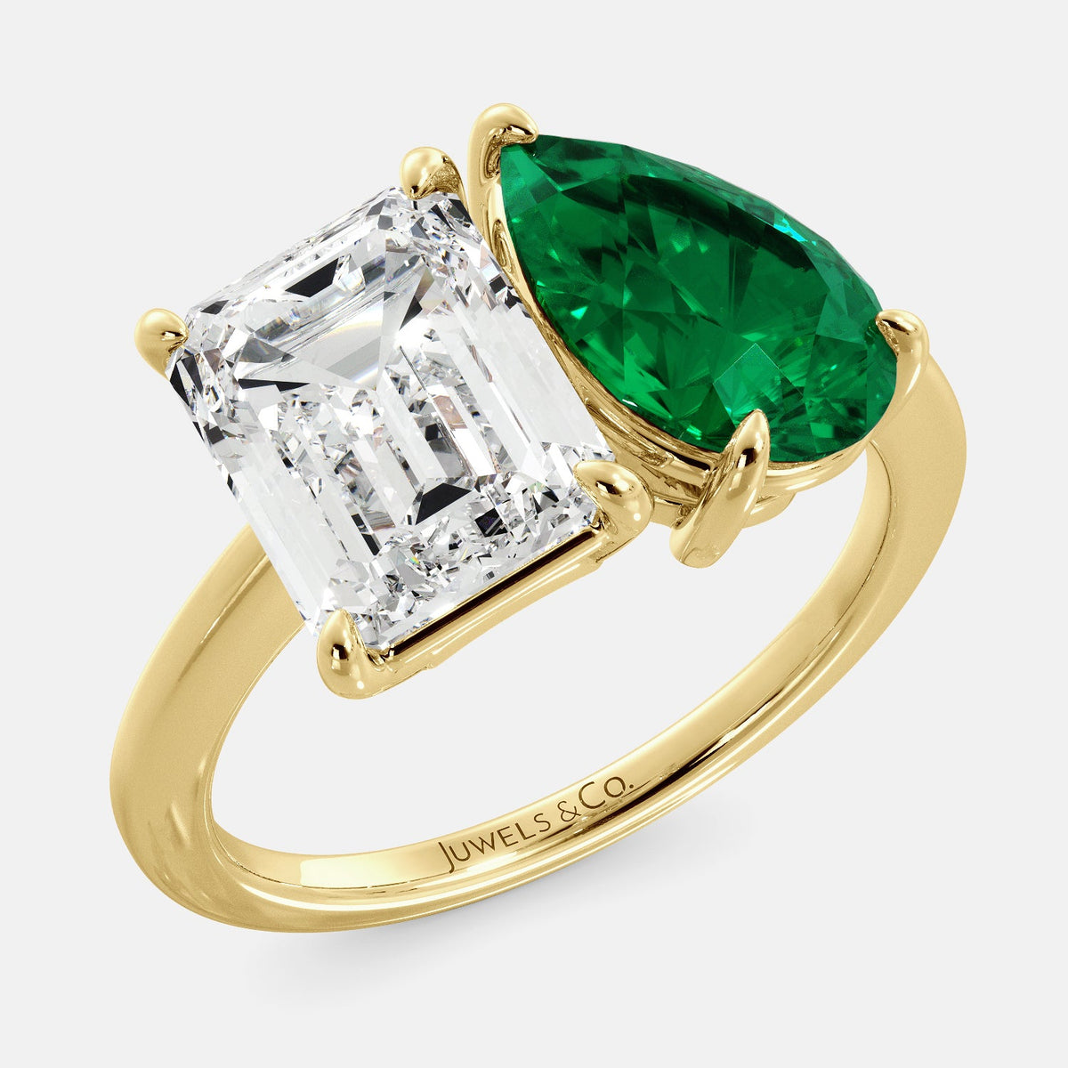 A toi et moi ring with an emerald-cut white topaz and a pear-cut gemstone. The emerald-cut morganite is set on the left of the ring, and the pear-cut gemstone is set on the right. The ring is made of recycled yellow gold and has a simple, elegant design. The pear-cut gemstone can be customized. **Here are some additional details about the image:** * The emerald-cut white topaz is a birthstone for April. * The pear-cut gemstone can be customized to any stone of your choice.