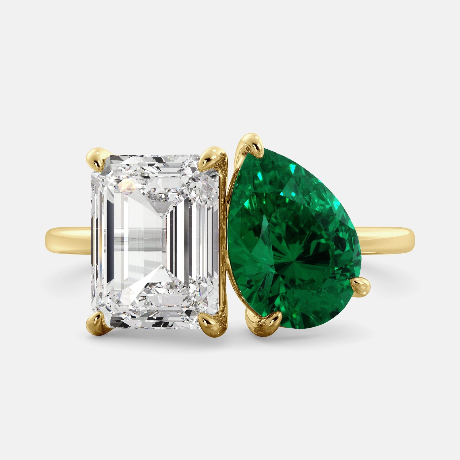 A toi et moi ring with an emerald-cut white topaz and a pear-cut gemstone. The emerald-cut morganite is set on the left of the ring, and the pear-cut gemstone is set on the right. The ring is made of recycled yellow gold and has a simple, elegant design. The pear-cut gemstone can be customized. **Here are some additional details about the image:** * The emerald-cut white topaz is a birthstone for April. * The pear-cut gemstone can be customized to any stone of your choice.