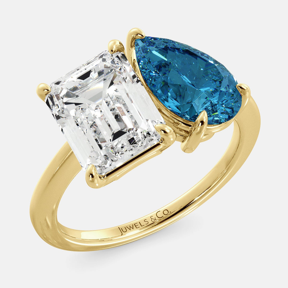 A toi et moi ring with an emerald-cut white topaz and a pear-cut gemstone. The emerald-cut morganite is set on the left of the ring, and the pear-cut gemstone is set on the right. The ring is made of recycled yellow gold and has a simple, elegant design. The pear-cut gemstone can be customized. **Here are some additional details about the image:** * The emerald-cut white topaz is a birthstone for April. * The pear-cut gemstone can be customized to any stone of your choice.