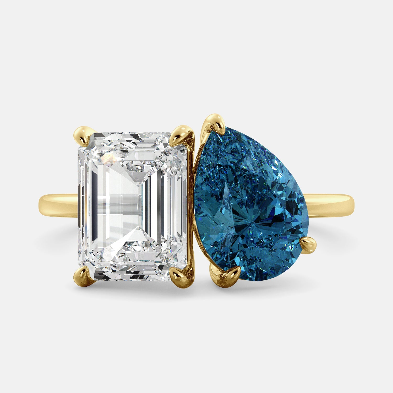 A toi et moi ring with an emerald-cut white topaz and a pear-cut gemstone. The emerald-cut morganite is set on the left of the ring, and the pear-cut gemstone is set on the right. The ring is made of recycled yellow gold and has a simple, elegant design. The pear-cut gemstone can be customized. **Here are some additional details about the image:** * The emerald-cut white topaz is a birthstone for April. * The pear-cut gemstone can be customized to any stone of your choice.