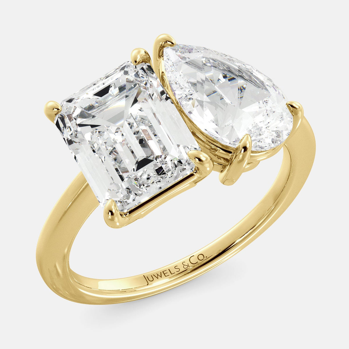 A toi et moi ring with an emerald-cut white topaz and a pear-cut gemstone. The emerald-cut morganite is set on the left of the ring, and the pear-cut gemstone is set on the right. The ring is made of recycled yellow gold and has a simple, elegant design. The pear-cut gemstone can be customized. **Here are some additional details about the image:** * The emerald-cut white topaz is a birthstone for April. * The pear-cut gemstone can be customized to any stone of your choice.