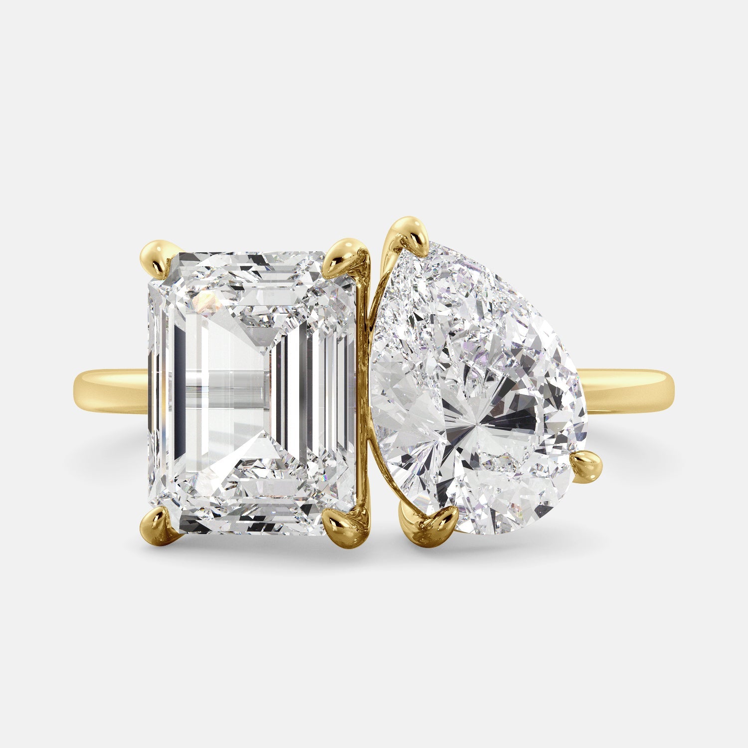 A toi et moi ring with an emerald-cut white topaz and a pear-cut gemstone. The emerald-cut morganite is set on the left of the ring, and the pear-cut gemstone is set on the right. The ring is made of recycled yellow gold and has a simple, elegant design. The pear-cut gemstone can be customized. **Here are some additional details about the image:** * The emerald-cut white topaz is a birthstone for April. * The pear-cut gemstone can be customized to any stone of your choice.