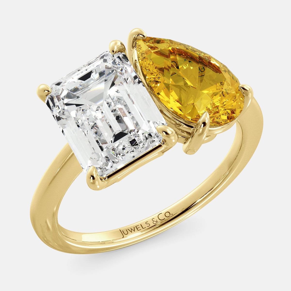 A toi et moi ring with an emerald-cut white topaz and a pear-cut gemstone. The emerald-cut morganite is set on the left of the ring, and the pear-cut gemstone is set on the right. The ring is made of recycled yellow gold and has a simple, elegant design. The pear-cut gemstone can be customized. **Here are some additional details about the image:** * The emerald-cut white topaz is a birthstone for April. * The pear-cut gemstone can be customized to any stone of your choice.