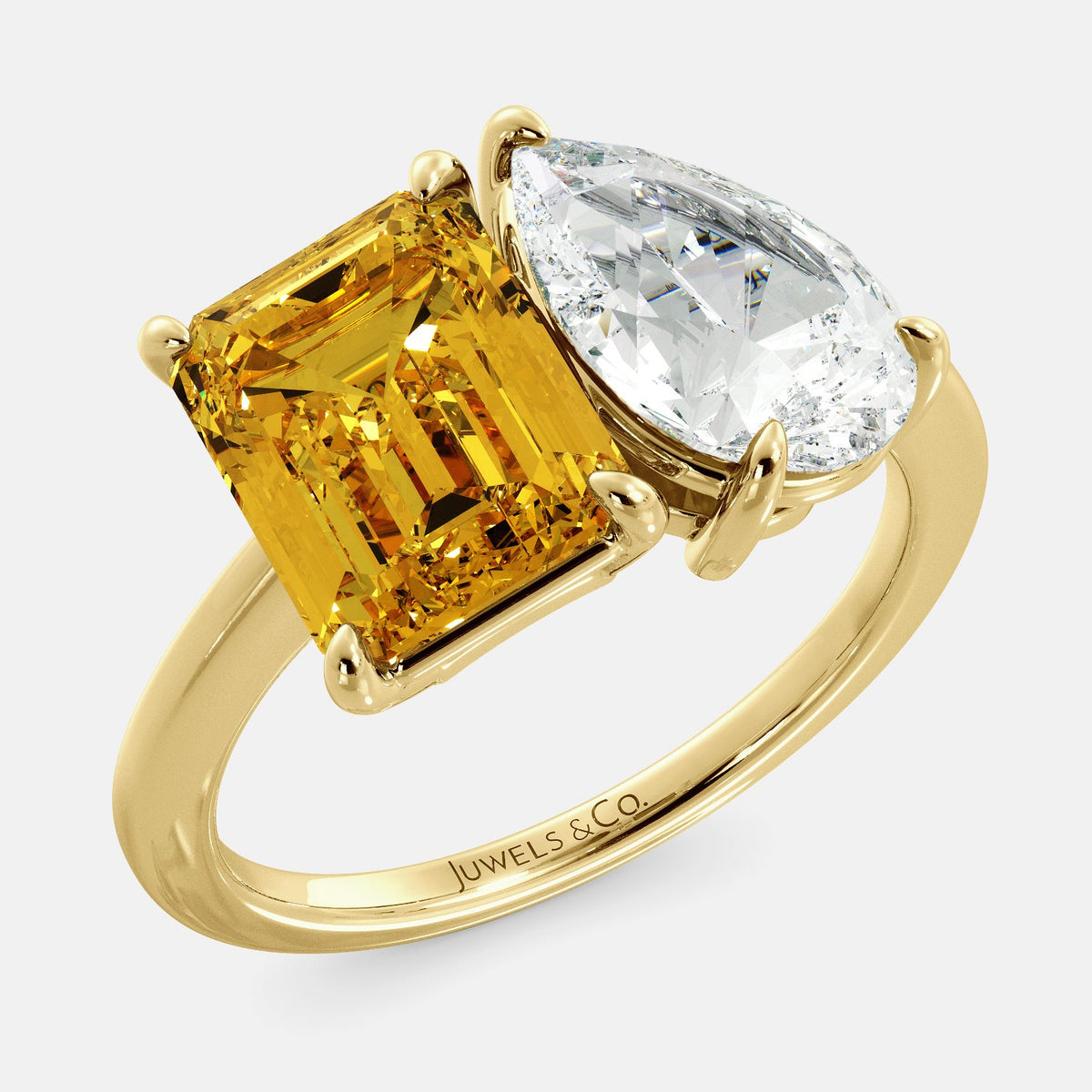 A toi et moi ring with an emerald-cut Citrin and pear-cut gemstone. The emerald-cut morganite is set on the left of the ring, and the pear-cut gemstone is set on the right. The ring is made of recycled yellow gold and has a simple, elegant design. The pear-cut gemstone can be customized. **Here are some additional details about the image:** * The emerald-cut white Citrin is a birthstone for November. * The pear-cut gemstone can be customized to any stone of your choice.