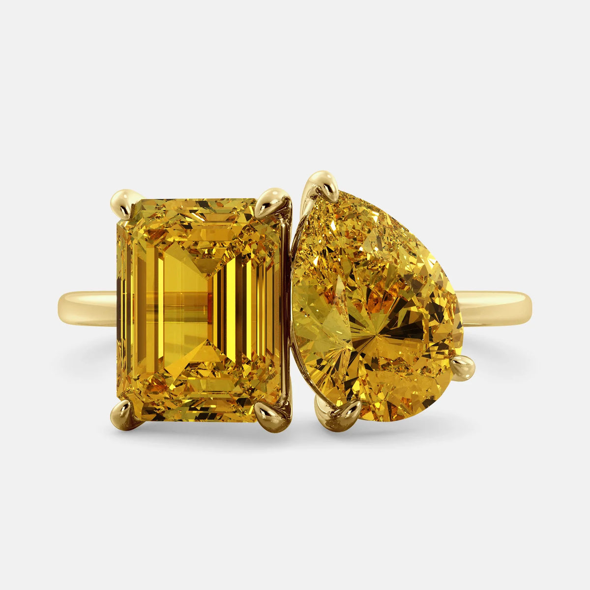 A toi et moi ring with two citrine gemstones. The first gemstone is an emerald cut, and the second gemstone is a pear shape. The ring is made of 14k yellow gold and is set on a dainty band. The gemstones are sparkling in the light and are a beautiful and meaningful piece of jewelry.